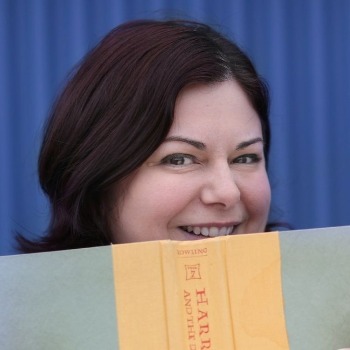 Headshot of Megan with face partially hidden behind book